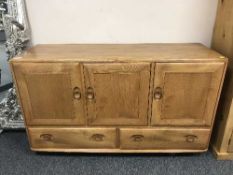 An Ercol elm triple door low sideboard