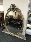 A Victorian oval gilt framed over mantel mirror with cherub design and candle sconces