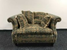A Barker and Stonehouse love seat upholstered in green and gold print with scatter cushions