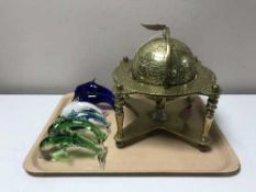 A heavy brass globe on stand together with six glass dolpin ornaments
