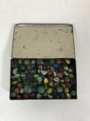 An antique tin containing marbles