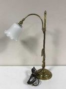 A rise and fall brass table lamp with white glass shade