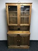 A Ducal pine glazed display cabinet fitted with cupboards beneath