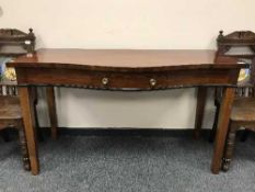An antique serpentine fronted mahogany console table fitted with a drawer