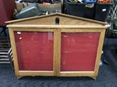 An oak double door notice board cabinet