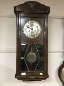An early twentieth century oak wall clock with pendulum