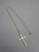 A white gold diamond set crucifix pendant suspended upon a sterling silver chain.