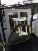 An ornate white framed mirror and a shaped framed mirror