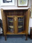 An Art Nouveau inlaid mahogany display cabinet with bow fronted leaded glass doors,