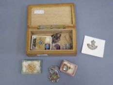 A wooden trinket box containing costume jewellery, badges, Victorian locket,