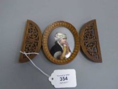 An antique wooden framed painted porcelain plaque depicting a young girl