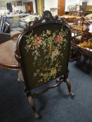 A Victorian mahogany fire screen inset needlework panel