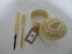 A carved bone trinket box depicting elephants, carved bangle,