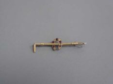 An Edwardian gold bar brooch modelled as a riding crop set with diamond and ruby horseshoe