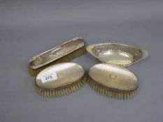 A pair of silver backed dressing table brushes together with a small silver dish and a further