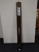 A lacquered metal ship's barometer on oak panel