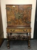 A burr walnut brass mounted cocktail cabinet on ornate carved stand,