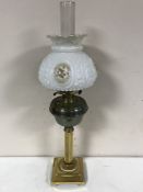 An antique brass oil lamp with brass shade and chimney