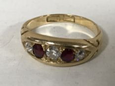 An early twentieth century 18ct gold three stone diamond and ruby ring, 4.4g, ring size M.