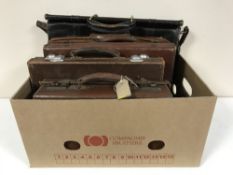 A box containing three small vintage leather luggage cases,