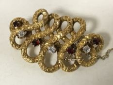 A 14ct gold diamond and ruby swirl brooch, 10.
