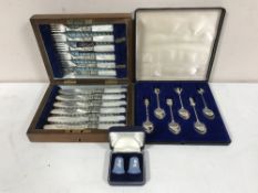 A cased set of six white metal spoons with finial decorations together with a cased set of desert