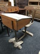 An early 20'th century school desk with fixed chair and footrests.