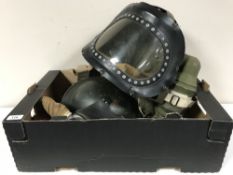 A collection of vintage gas masks and a Brodie helmet