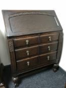 A carved oak bureau fitted three drawers