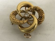 A 14ct yellow gold swirl brooch, set with a single diamond, 4.