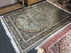 A fringed Persian Kashan rug on green ground,