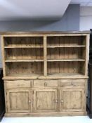 A large set of pine open shelves fitted three drawers and cupboards below