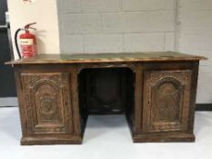 An antique oak and mahogany twin pedestal desk with carved panel doors inset green leather panel