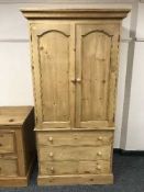 A pine double door wardrobe fitted with three drawers