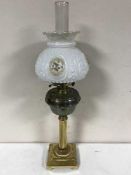 An antique brass oil lamp with brass shade and chimney