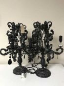 A set of three black ornate table lamps with glass drops
