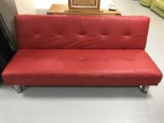 A contemporary red leather folding bed settee