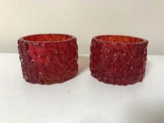 A pair of ruby red Whitefriars cylindrical bark candle holders designed by Geoffrey Baxter,