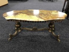 A shaped onyx topped coffee table on a brass base
