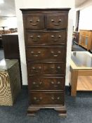 A walnut seven-drawer chest with brass drop handles on bracket feet