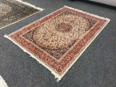 A fringed Persian Kashan rug on red and cream ground,