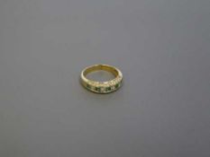 An 18ct gold emerald and diamond half eternity ring