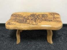 A carved pine coffee table depicting horses ploughing a field