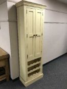 A painted pine two door cabinet with bottle rack below