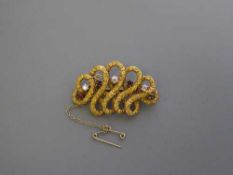 A 14ct gold diamond and ruby swirl brooch, 10.