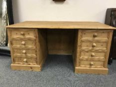 A large pine twin pedestal desk fitted with eight drawers