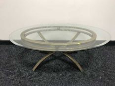 An oval glass top coffee table on a metal base