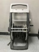 A hose pipe on trolley and a large plastic garden planter