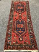 A fringed wool Persian runner on red ground