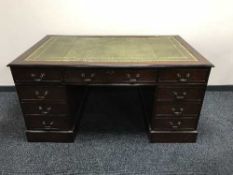 A mahogany twin pedestal writing desk fitted nine drawers with green leather inset panel